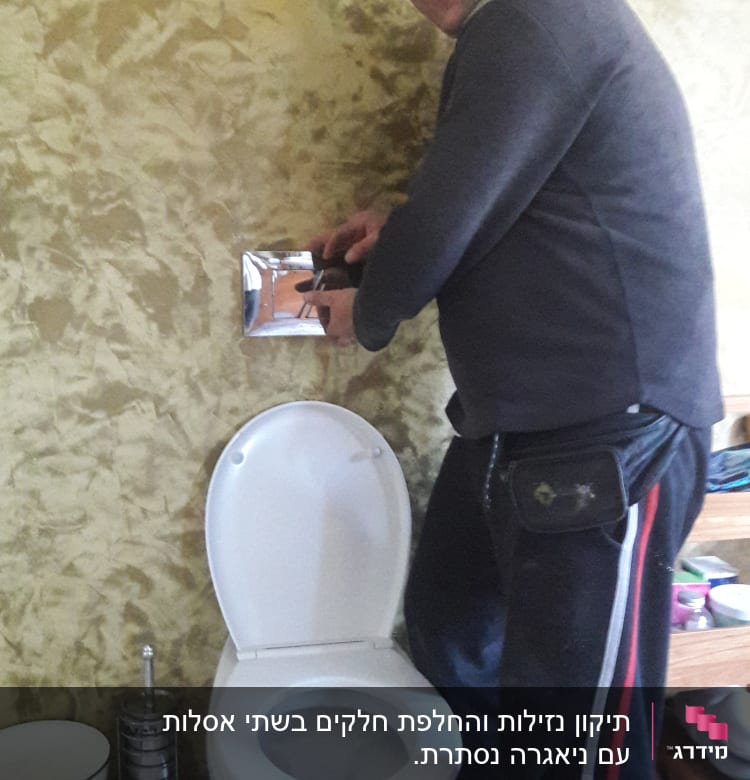 אדם מתקן לחצן ניאגרה בשירותים